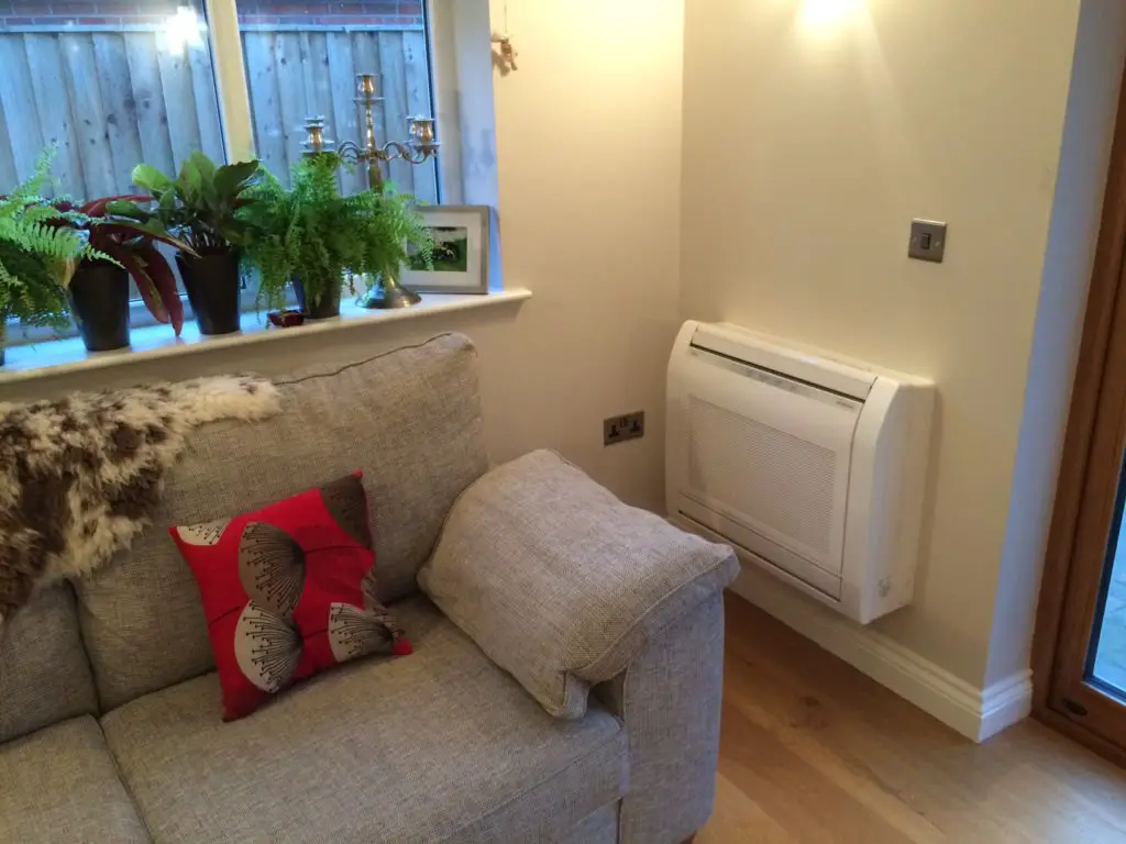 Picture of a heat pump on a wall next to a sofa