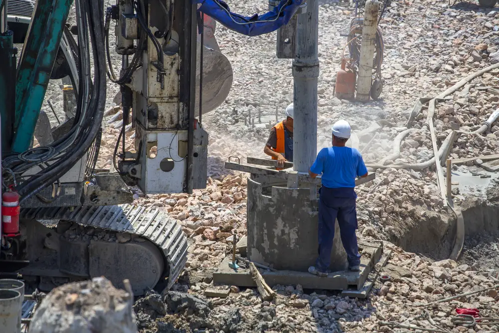 Workers on a rotary drilling machine heavy equipment.